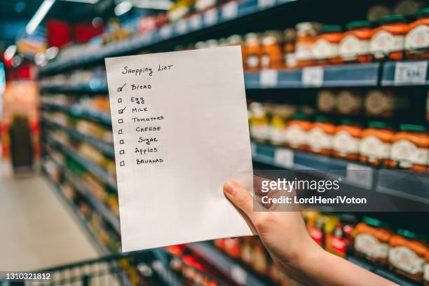 woman with shopping list in grocery store - list imagens e fotografias de stock