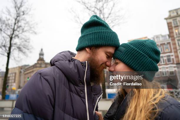 a loving couple man and woman in winter warm clothes embracing - green hat fotografías e imágenes de stock