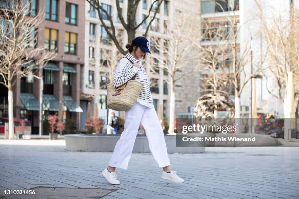 Fashion blogger Patricia Wirschke is seen wearing a Les Copains striped polo shirt, Seductive white pants, a Celine basket bag, Celine baseball cap,...