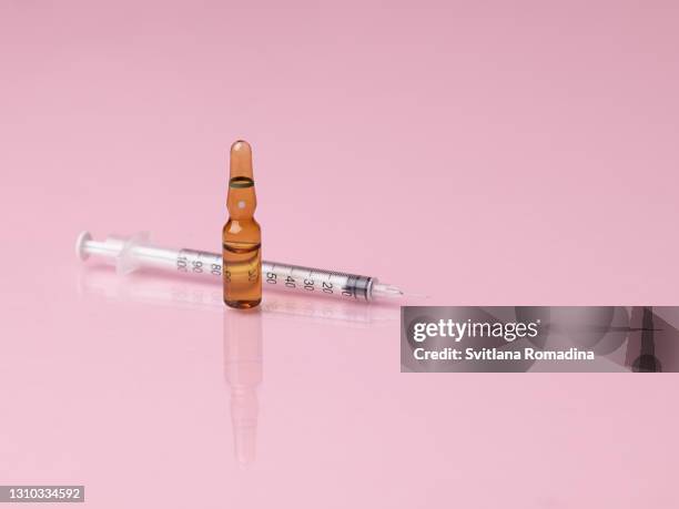 brown ampoule and syringe on glass reflected surface - steroids stock pictures, royalty-free photos & images