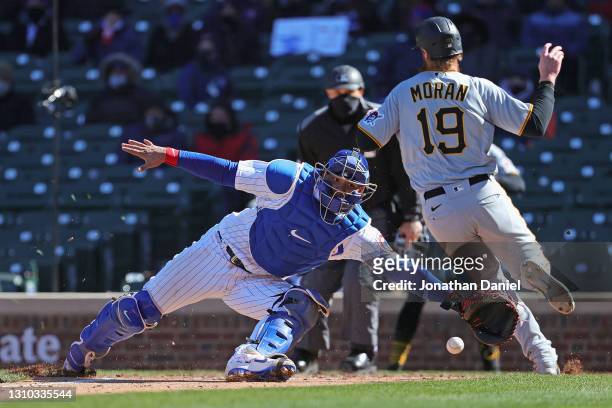 Willson Contreras of the Chicago Cubs dives for a relay throw as Colin Moran of the Pittsburgh Pirates runs past to score a run in the fifth inning...