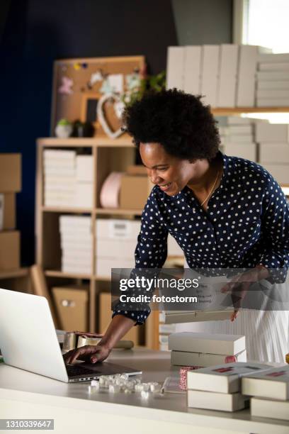 businesswoman preparing ''thank you'' care packages and using laptop - care package stock pictures, royalty-free photos & images