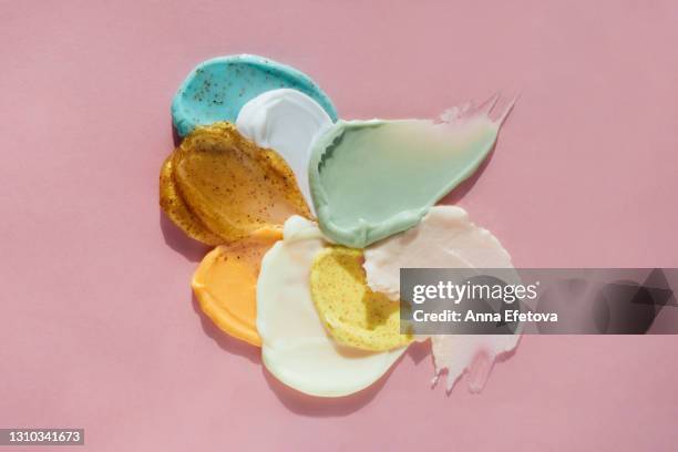 set multicolored smears of illuminating yellow scrub with exfoliating particles and white, beige, rose, turquoise and orange creams on rose background. selfcare is a trendy procedure of the year - säure stock-fotos und bilder