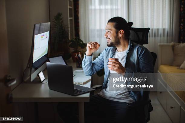 young man using desktop pc at desk in home office - bitcoin phone stock pictures, royalty-free photos & images