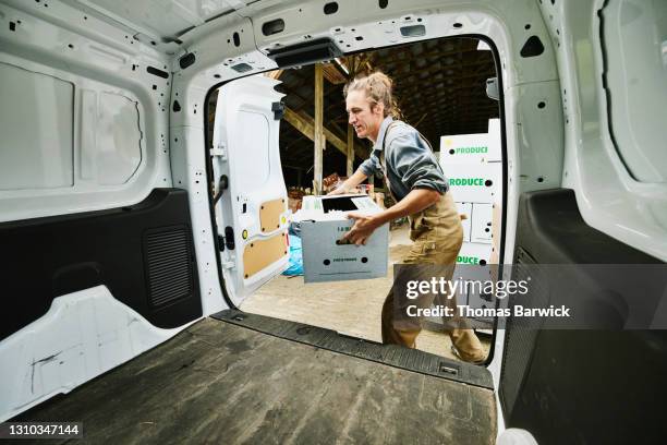 wide shot of farmer putting freshly packed csa boxes into delivery van - organic farm stock-fotos und bilder