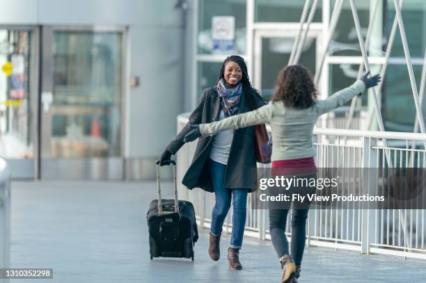 dos amigos saludándose en el aeropuerto - reencuentro fotografías e imágenes de stock