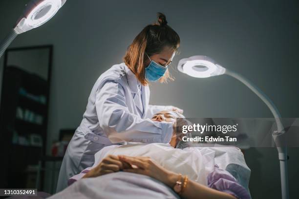 beautician cleaning asian chinese woman face with cotton ball before the operation start in surgery room waiting for treatment - woman applying cotton ball stock pictures, royalty-free photos & images