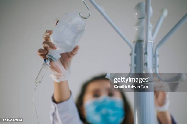 asian chinese female nurse preparing hanging saline solution - preparing drug in hospital nurse stock pictures, royalty-free photos & images