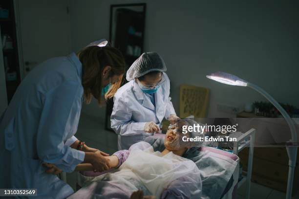 asian chinese cosmetologist is applying moisturizing on patient's face, drawing blood from patient's vein from arm  woman skin procedure. natural cosmetic products. facial treatment - human head veins stock pictures, royalty-free photos & images