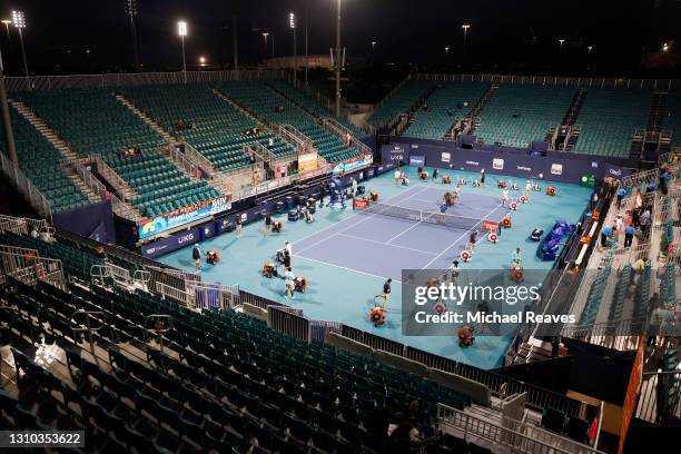 Miami Open staff work to dry the court after rain delayed the quarterfinal match between Andrey Rublev of Russia and Sebastian Korda of the United...