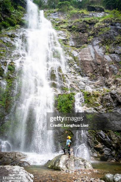 a male climber in front of a waterfall - waterfall-jump stock pictures, royalty-free photos & images
