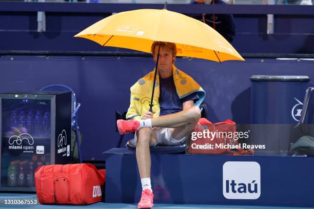 Sebastian Korda of the United States covers himself with a umbrella as rain begins to fallagainst Andrey Rublev of Russia in their quarterfinal match...