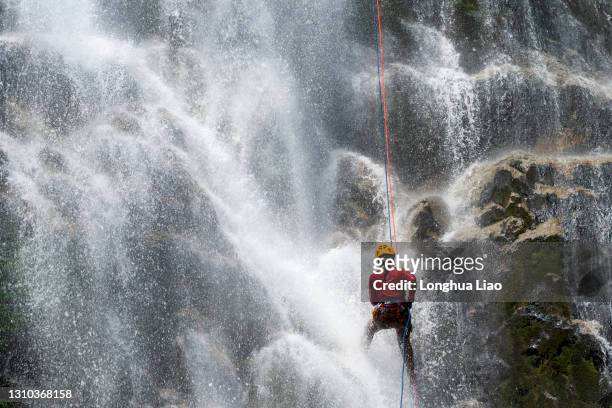 a male climber falls into a waterfall - 爬山繩 個照片及圖片檔