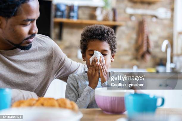 single black father taking care of his sick son at home. - blowing nose stock pictures, royalty-free photos & images