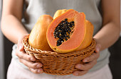 Ripe papaya fruit in a basket holding by woman hand