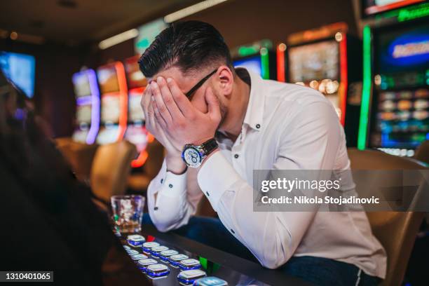 young man loosing his money on slot machines - problem gambling stock pictures, royalty-free photos & images