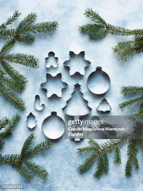 still life of metal cookie cutters with christmas tree twigs - pastry cutter stockfoto's en -beelden