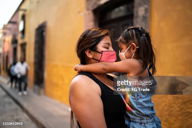 mutter und tochter umarmen im freien - tragen gesichtsmaske - lateinamerika stock-fotos und bilder