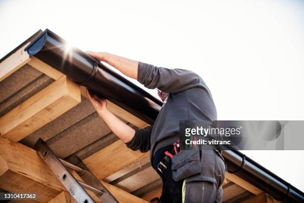 worker on roof installing gutter - installation stock pictures, royalty-free photos & images