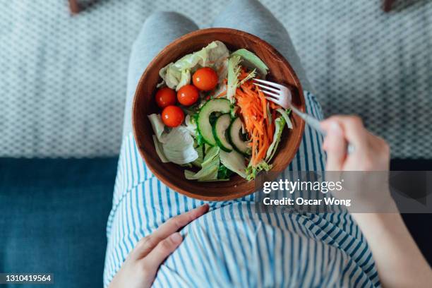 overhead shot of pregnant woman eating vegetable salad - woman salad stockfoto's en -beelden
