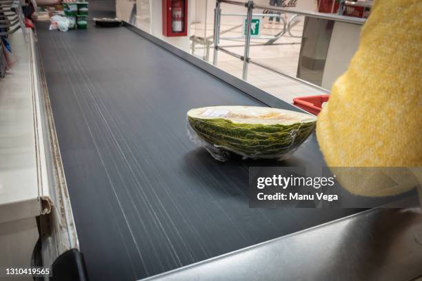 a person putting a fruit on the supermarket checkout tape. - kassa stockfoto's en -beelden