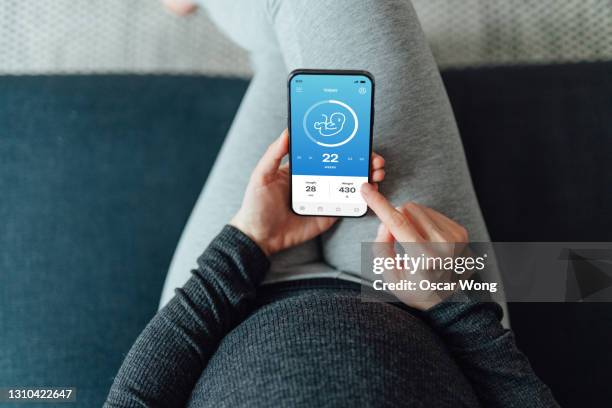 high angle view of pregnant woman using pregnancy app on smartphone - smart communicate elevation view stock-fotos und bilder