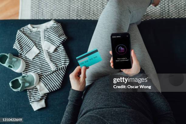 high angle view of pregnant woman doing online shopping with smartphone and credit card - babybekleidung stock-fotos und bilder