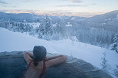 Woman resting in hot tub with view on mountains in winter
