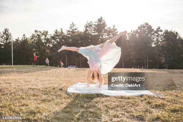 夏天在公園裡做手推車的年輕女孩 - girl in dress doing handstand 個照片及圖片檔