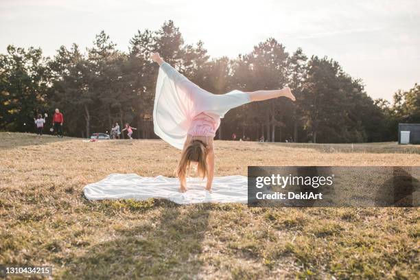 joven gimnasia haciendo ruedas de carro en el parque en el día de verano - girl in dress doing handstand fotografías e imágenes de stock