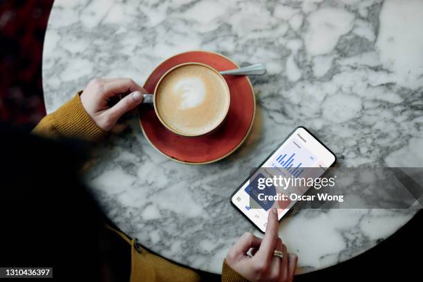 flat lay shot of young woman managing bank account online with smartphone - raised finger stock-fotos und bilder