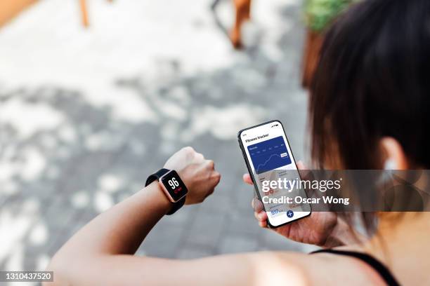 young woman using fitness tracker app on smart watch and smartphone - smartwatch imagens e fotografias de stock