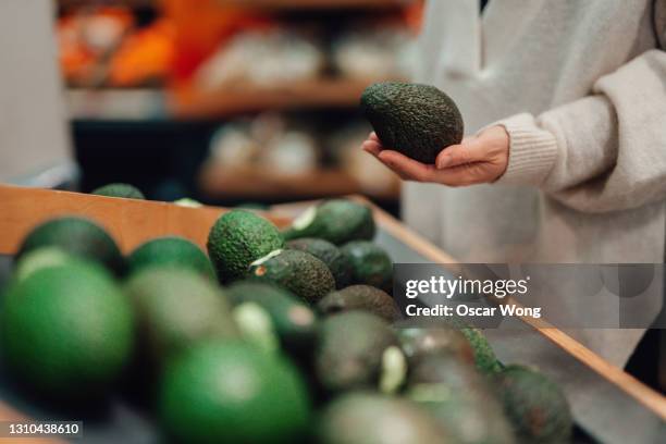 woman buying avocado at grocery store - avocado bildbanksfoton och bilder