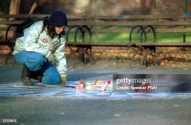 Woman places a rose on the "Imagine" memorial mosaic December 7, 2000 honoring the late John Lennon at Strawberry Fields in New York City''s Central...