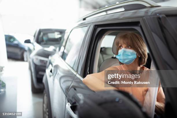 woman in car preparing for covid vaccination in drive-in covid vaccination centre - drive through mask stock pictures, royalty-free photos & images