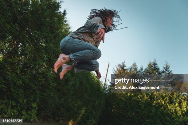 young woman in mid air, jumping on trampoline - trampoline jump stock pictures, royalty-free photos & images