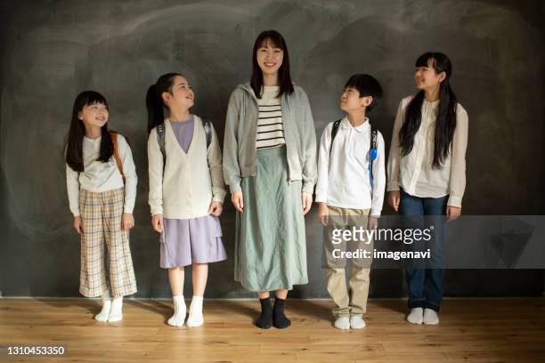 elementary school students and teacher standing in line - 12 23 monate stock-fotos und bilder