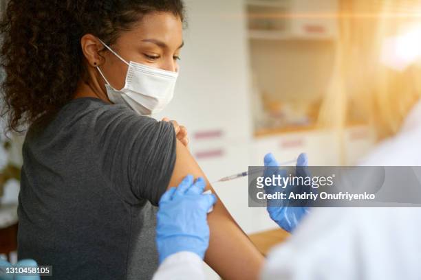young woman getting vaccinated - vacuna contra la covid 19 fotografías e imágenes de stock