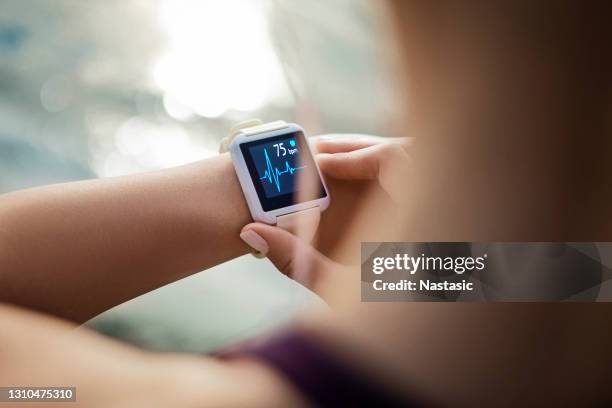 mujer mirando su reloj inteligente para un rastro de pulso - aplicación para móviles fotografías e imágenes de stock