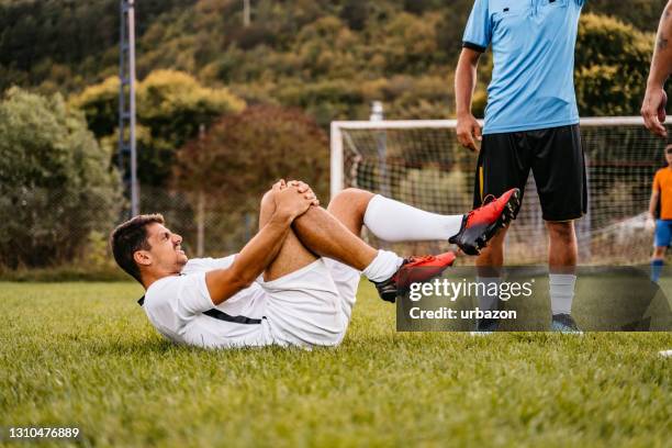 soccer player get got injured in the game - injured football player stock pictures, royalty-free photos & images