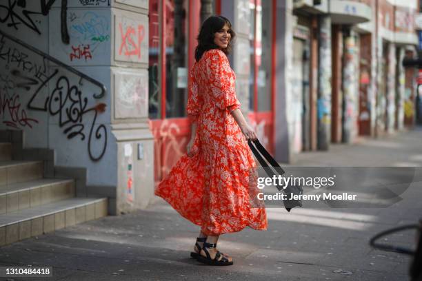 Anna Wolfers poses wearing red floral midi dress, black bag and black open toe sandals on March 30, 2021 in Hamburg, Germany.