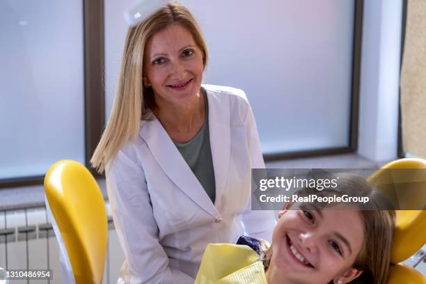 dentista che esamina i denti della bambina in clinica - supporto per mensola foto e immagini stock