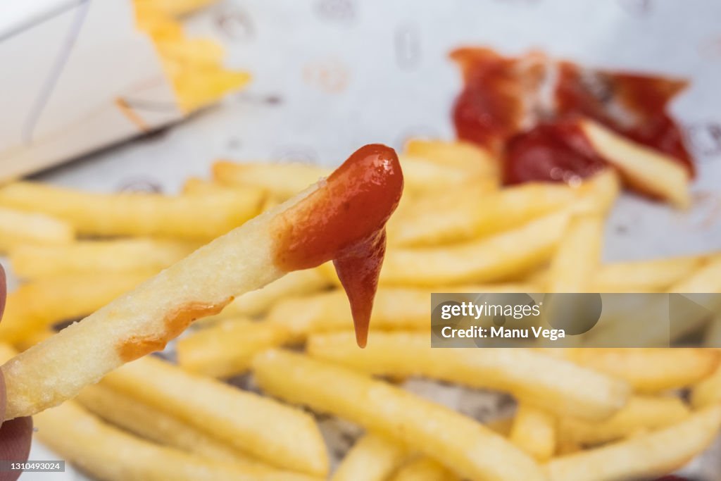 A person eating french fries with ketchup.