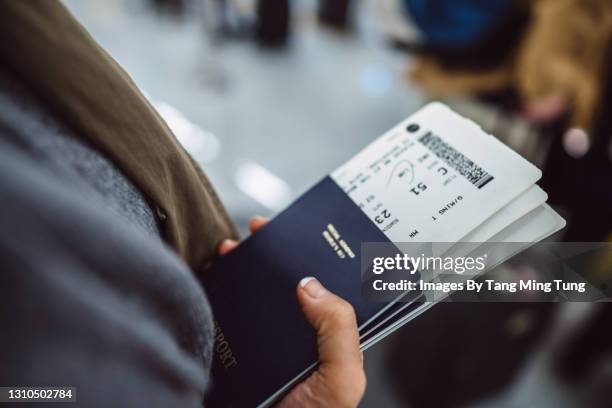 woman’s hands holding passports & boarding passes of her family while waiting at the check-in counter in the airport - airplane travel foto e immagini stock