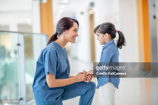 kvinnlig sjuksköterska ler mot en ung flicka patient - female nurse bildbanksfoton och bilder