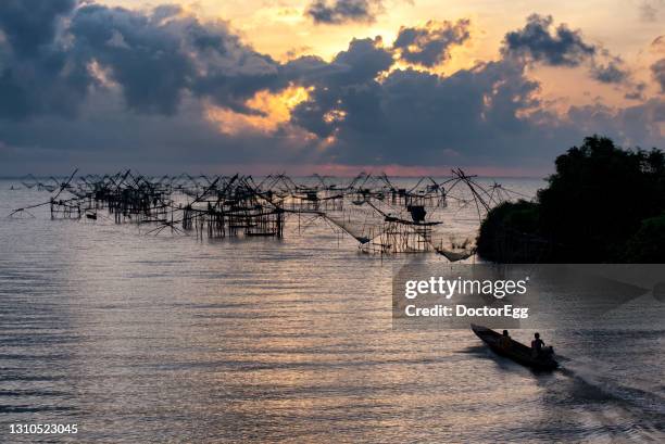 silhouette view of giant fisherman nets with fisherman boat at pak pra in twilight morning, phatthalung province, thailand - phatthalung province stock-fotos und bilder