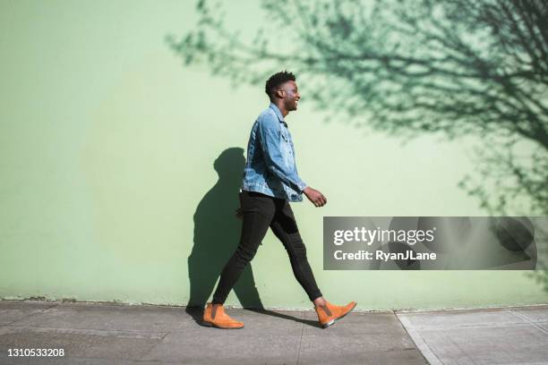 happy adult man walking sunny city street sidewalk - black jacket stock pictures, royalty-free photos & images