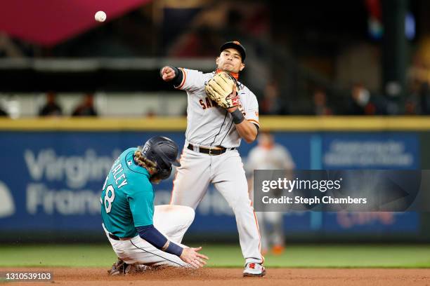 Donovan Solano of the San Francisco Giants turns a double play over Jake Fraley of the Seattle Mariners in the fourth inning at T-Mobile Park on...