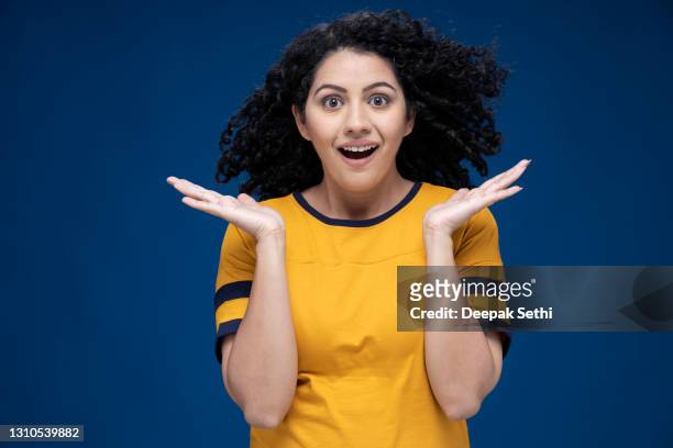 surprised women gesturing with arms having wide open eyes mouth isolated on blue background looking at camera:- stock photo - fashion model stock pictures, royalty-free photos & images