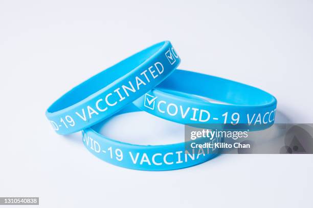 covid-19 vaccinated blue rubber wristband - rubber bracelet stock pictures, royalty-free photos & images